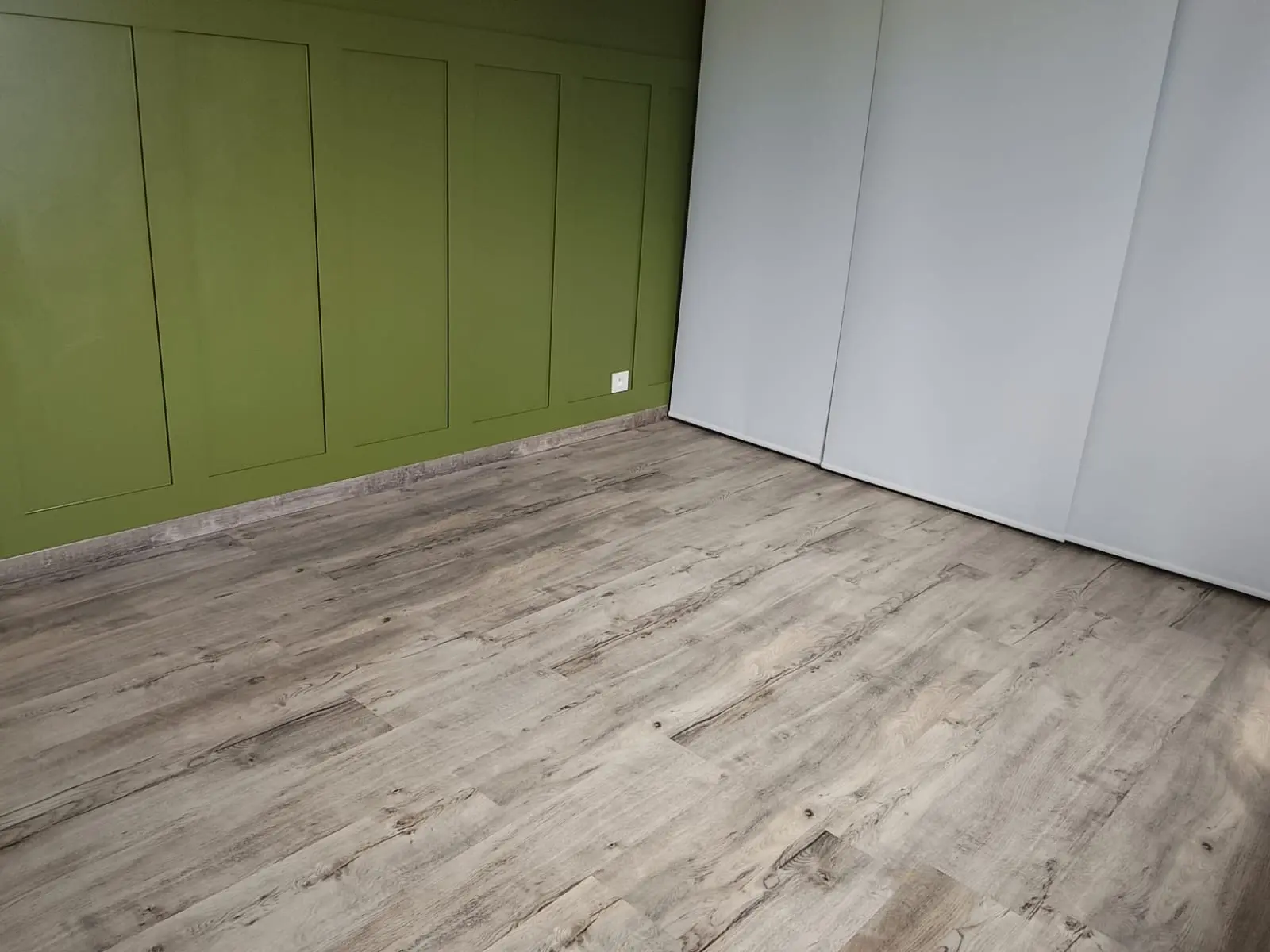 Chambre vide au mur vert, sol PVC et plinthes nettoyés