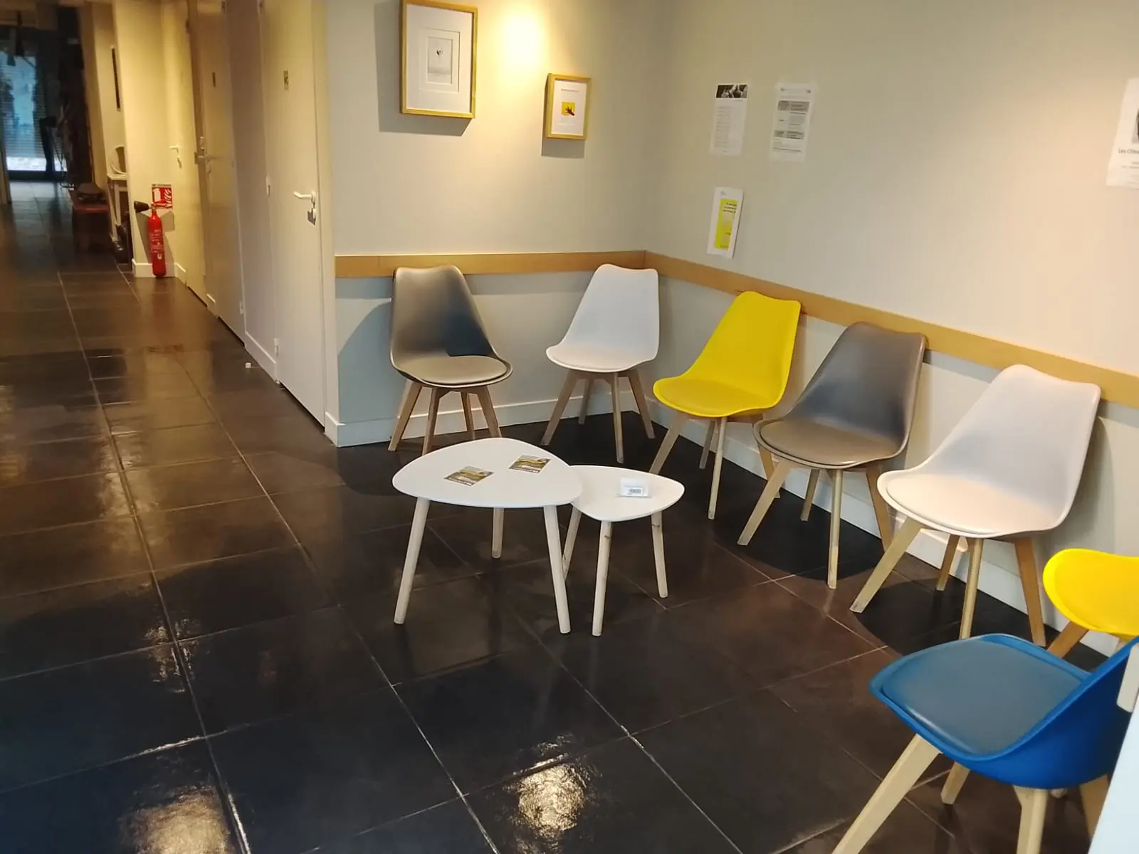Salle d'attente aux chaises alignées le long du mur, sol carrelé lavé