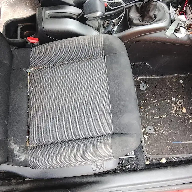 Siège passager encrassé et tapis de sol couvert de débris végétaux avant nettoyage